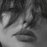 Monochrome close-up portrait of a woman with hair covering face, conveying mystery.